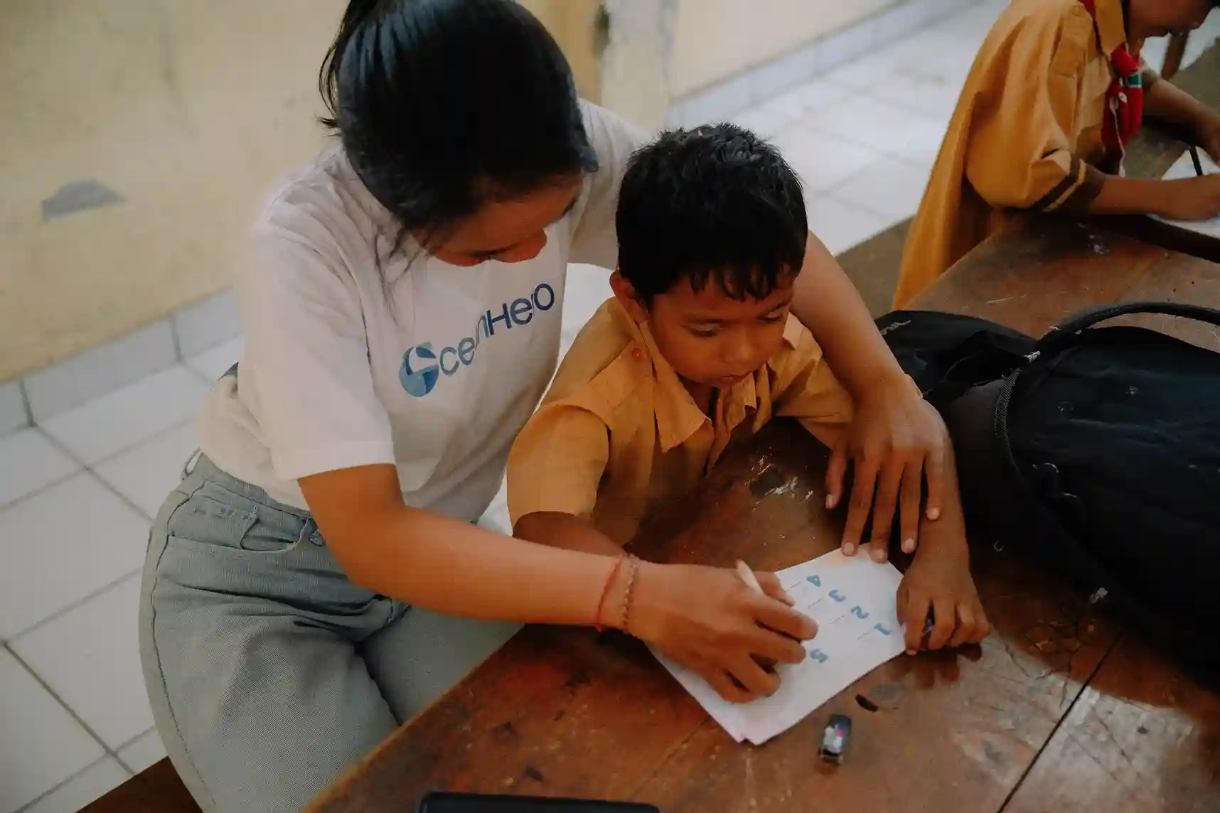 OceanHero volunteer teaching waste habits to a young student, guiding ocean conservation education