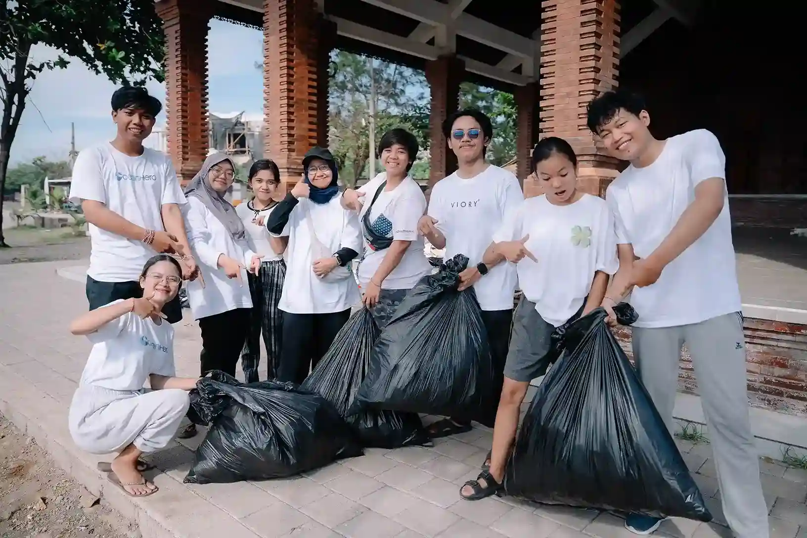 Students collecting trash bags at Padang Galak Beach cleanup, taking action for ocean conservation