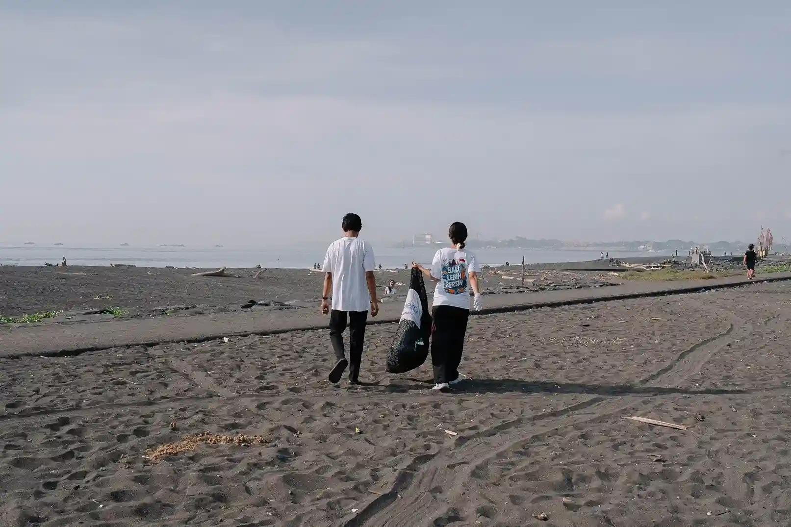 Two volunteers collecting plastic waste in bags during the 102 kg cleanup at Biaung Beach, Bali