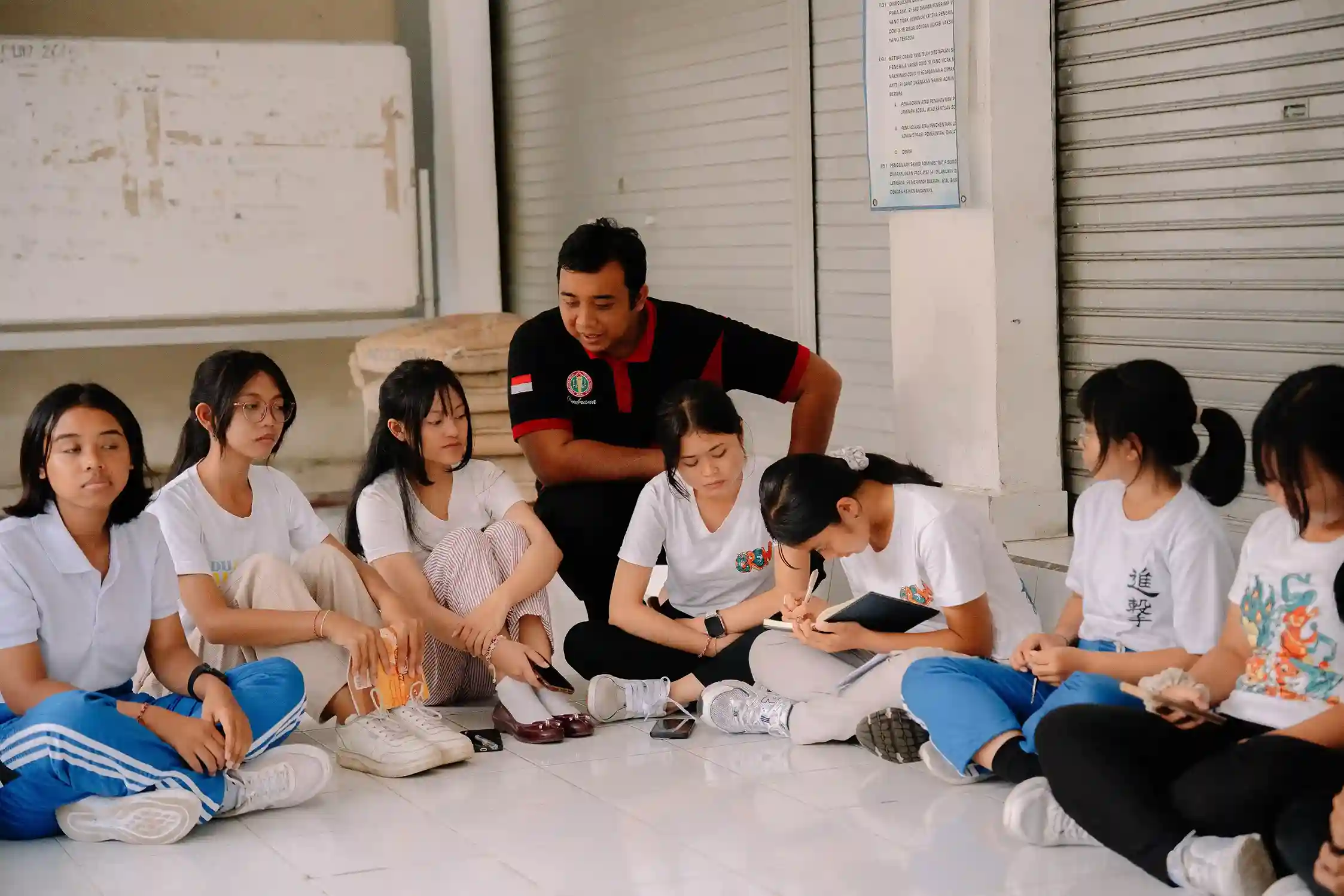 Students and teacher sit together on floor discussing ocean conservation action at SMAN 1 Negara