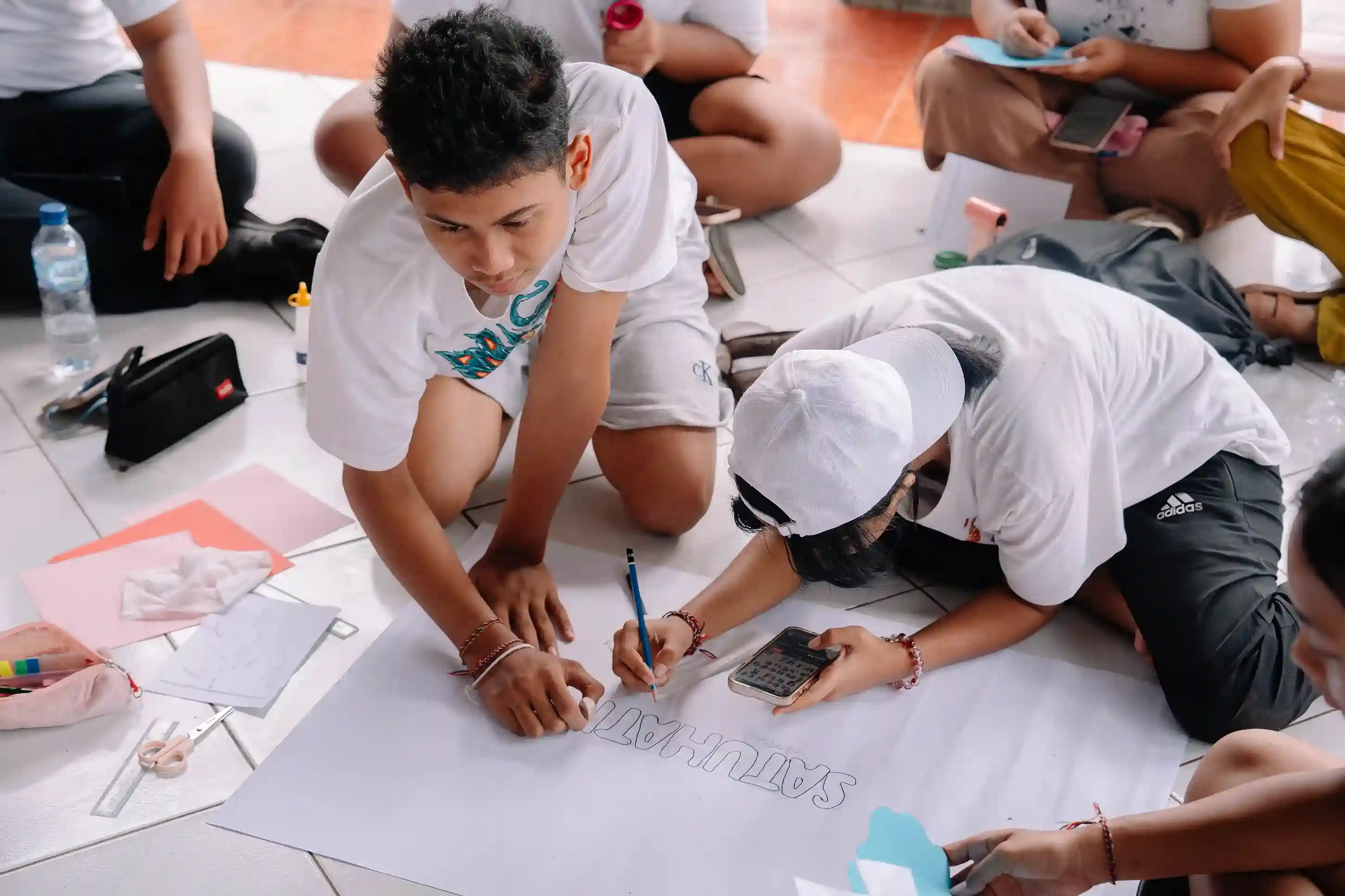 Students turning ideas into action, collaborating on a conservation awareness poster on the floor