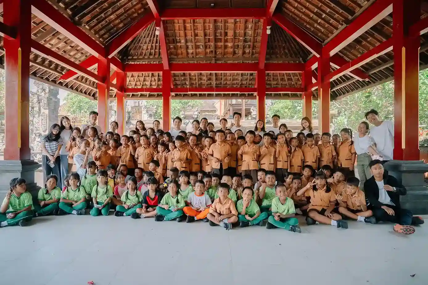 Students in uniforms gather under a traditional Balinese pavilion learning about waste and ocean conservation