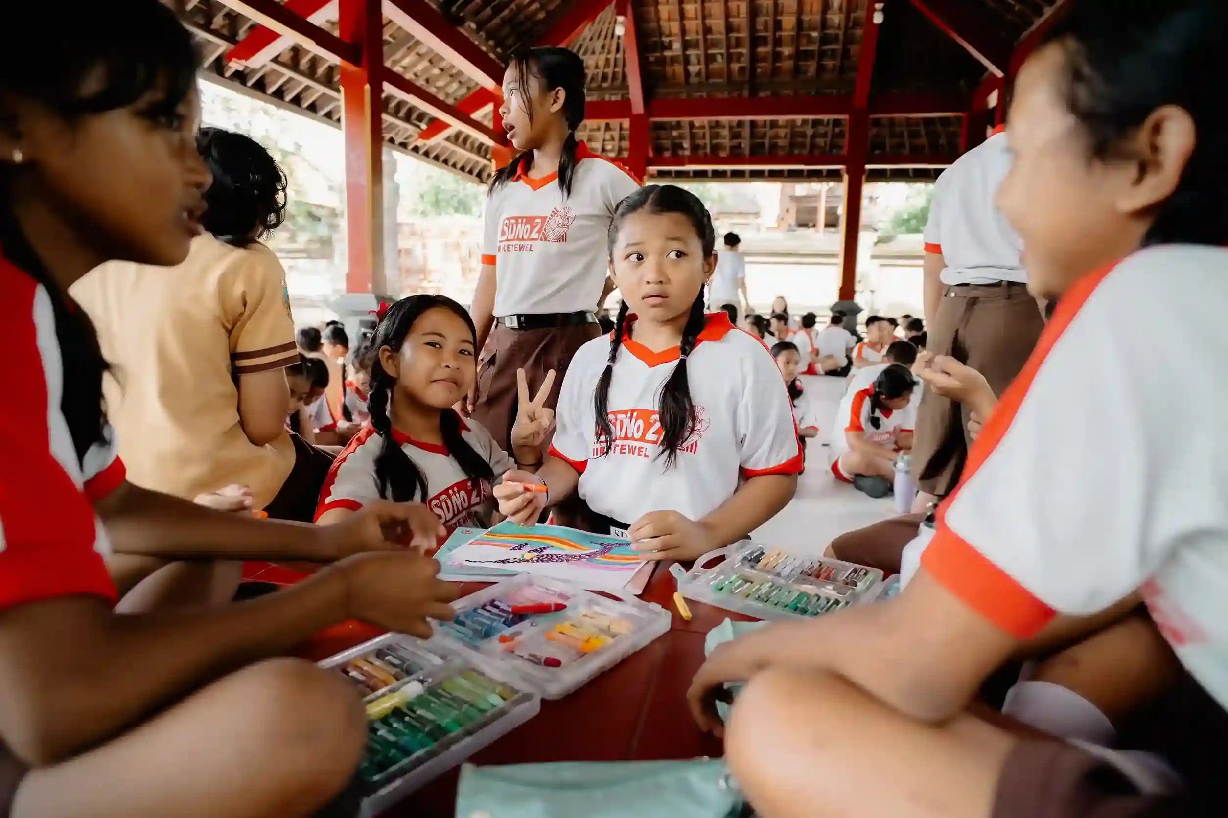 Students in school uniforms using art supplies, turning plastic bottles into purpose through creative education