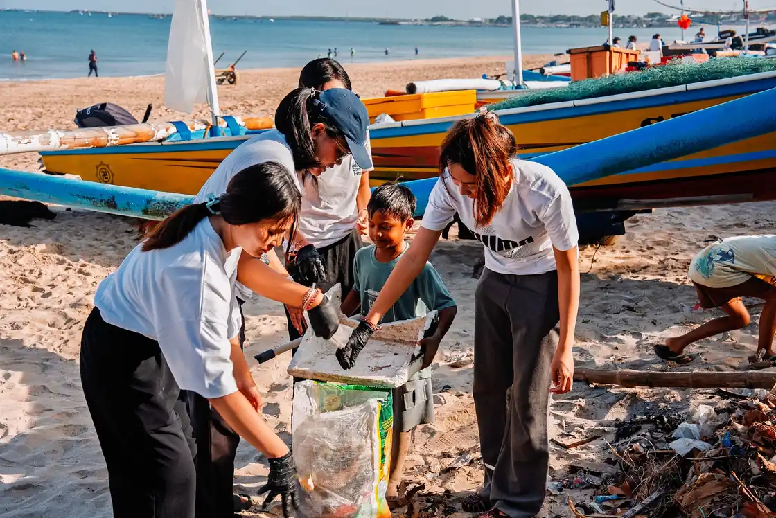 Volunteers filling waste bags during a beach clean-up at Kedonganan Beach