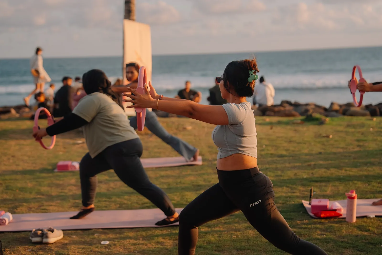 Participants mid-Pilates on mats at Seseh Beach, with the sea behind them