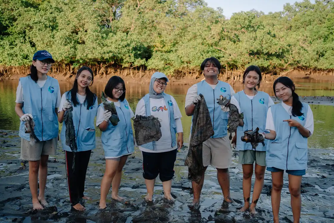 Volunteers holding up waste collected from the mangroves at Wana Segara Kertih