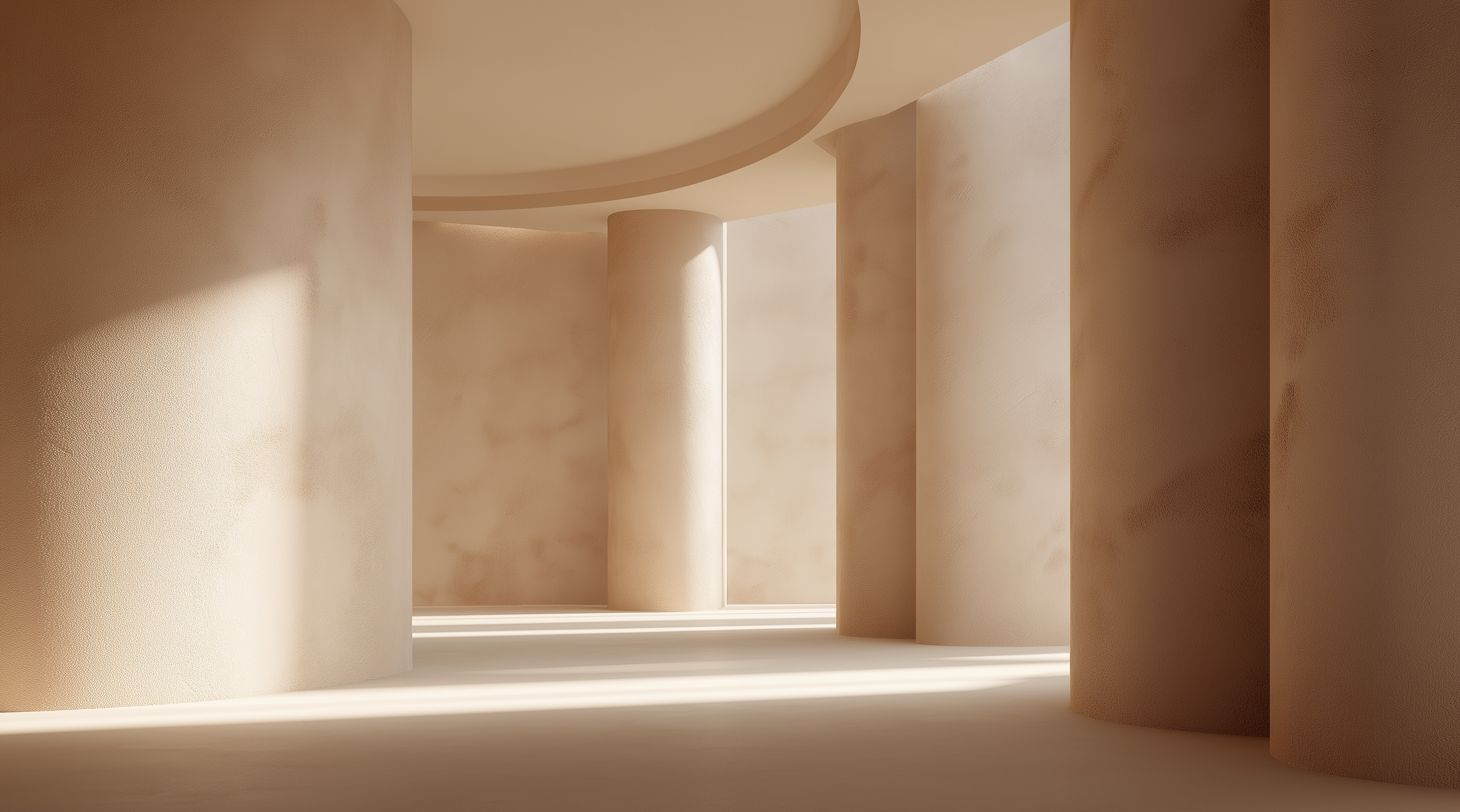 Intérieur minimaliste avec murs et colonnes beiges arrondis éclairés par la lumière naturelle.