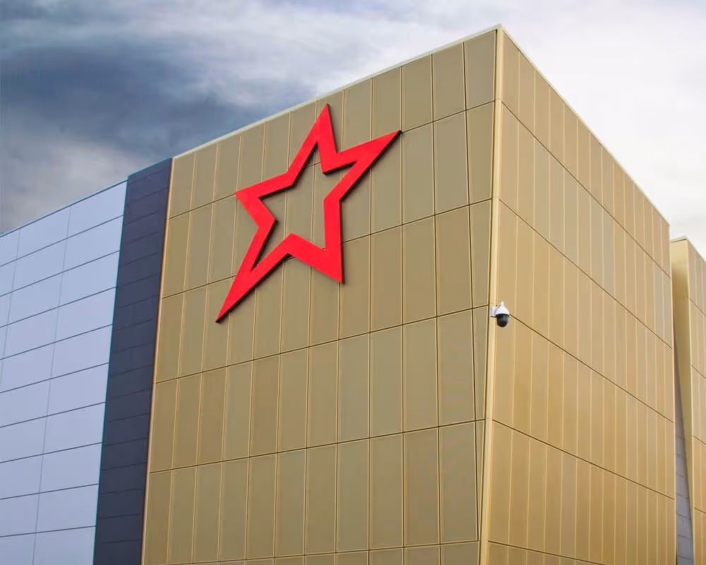 Modern building corner with gold and gray panels and a large red star emblem on the gold wall.