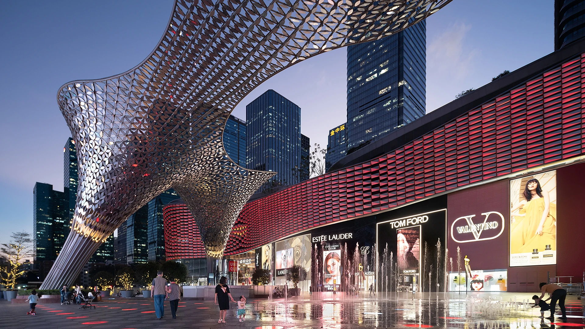 Futuristic plaza with curved metallic canopy, water fountains, and illuminated brand advertisements at dusk.