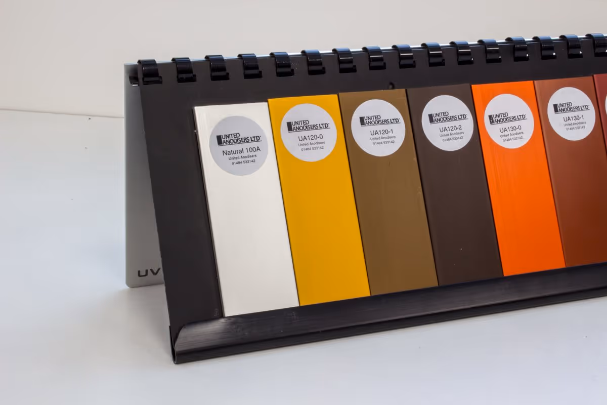 Color swatch display with samples from United Anodisers Ltd in shades from white to orange and brown.