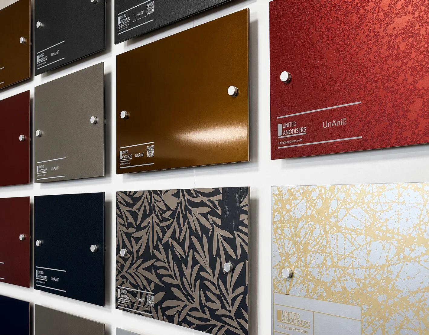 Wall display of anodized metal color and pattern samples from United Anodisers mounted with screws.