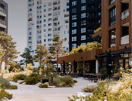 Patio urbain avec arbres, plantes et bancs entouré d'immeubles modernes hauts.