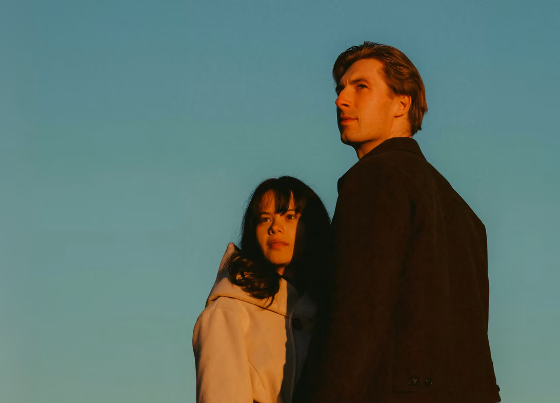 Un homme et une femme regardant l'horizon, couché de soleil.