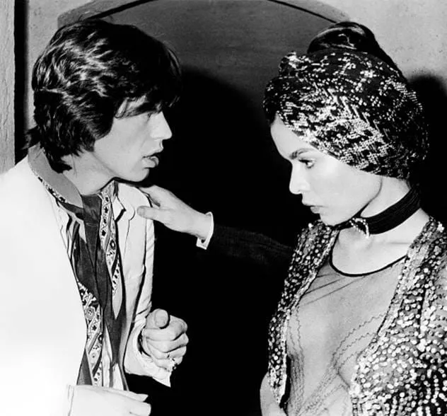Foto a preto e branco de Mick Jagger a falar com Bianca Jagger vestindo uma roupa de lantejoulas e turbante.