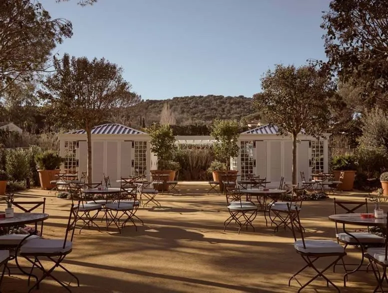 Elegante terraço exterior rodeado por oliveiras e vegetação no hotel AREV em Saint-Tropez.