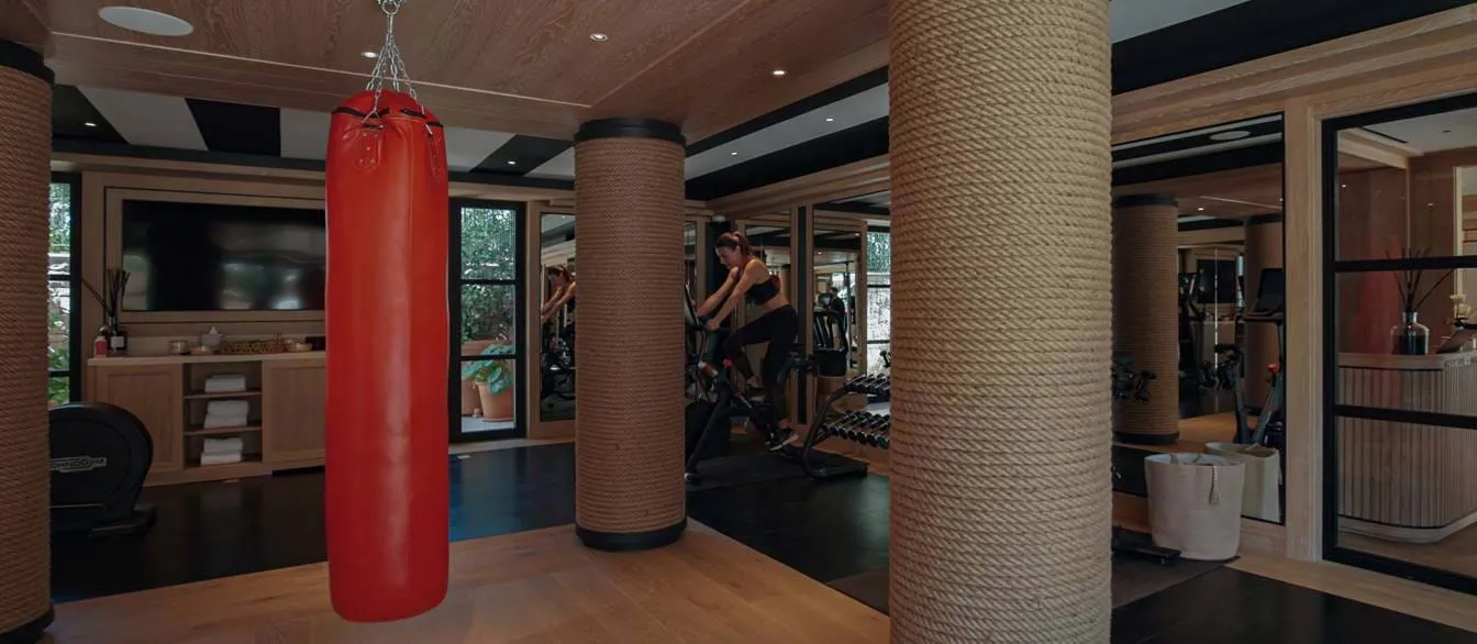 Equipamentos de fitness modernos e saco de pancadas vermelho no elegante ginásio do hotel AREV em Saint-Tropez.