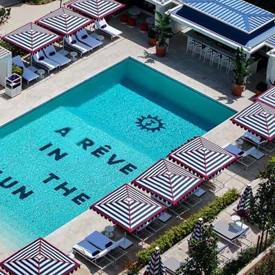 Vista aérea da piscina de luxo no hotel AREV em Saint-Tropez com as letras “A RÊVE IN THE SUN” no chão da piscina.