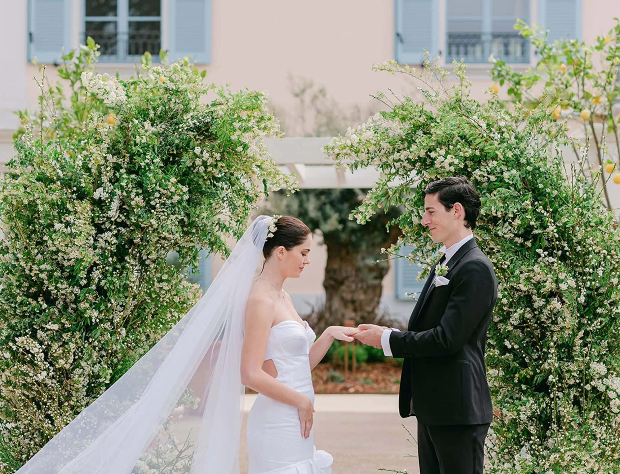 Momento romântico dos noivos trocando anéis sob um arco verdejante no AREV Hotel Saint-Tropez.