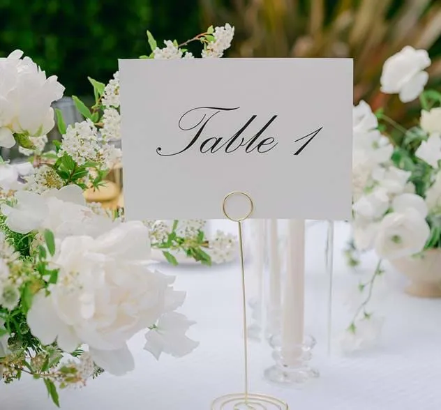 Detalhe de um elegante número de mesa entre arranjos florais brancos para um evento no AREV Saint-Tropez.