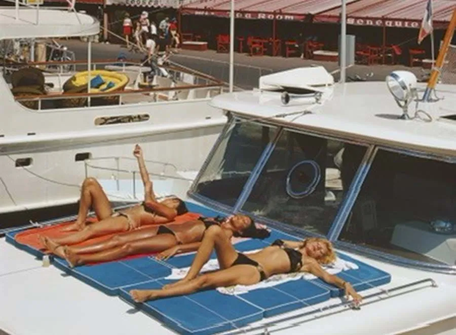 Três mulheres relaxando ao sol no convés superior de um iate de luxo atracado perto da AREV Saint-Tropez.