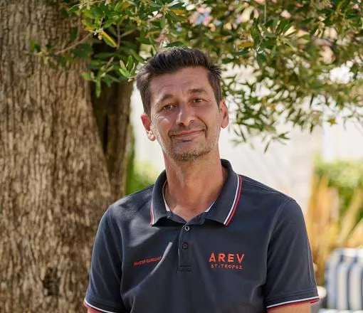 Recebedor membro da equipe do hotel AREV em Saint-Tropez em frente a uma oliveira.