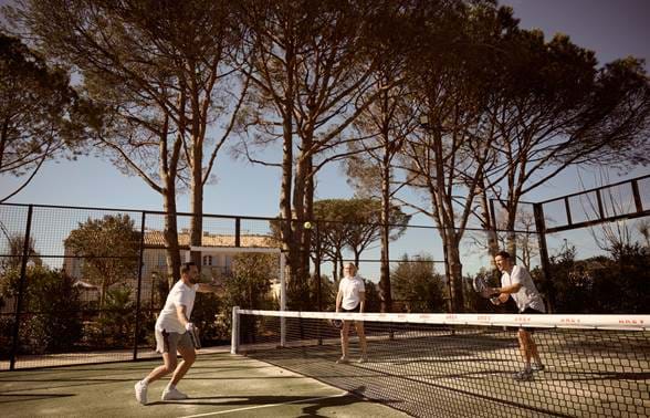 Jogo amigável de padel no campo privado rodeado por pinheiros no hotel AREV em Saint-Tropez.