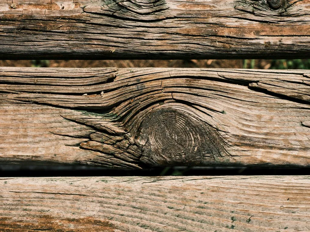 Nahaufnahme von verwitterten Holzdielen mit sichtbaren Maserungen und Rissen.