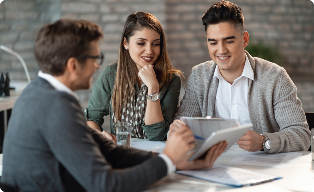 A man and woman reviewing documents with a professional advisor at a table in an office.