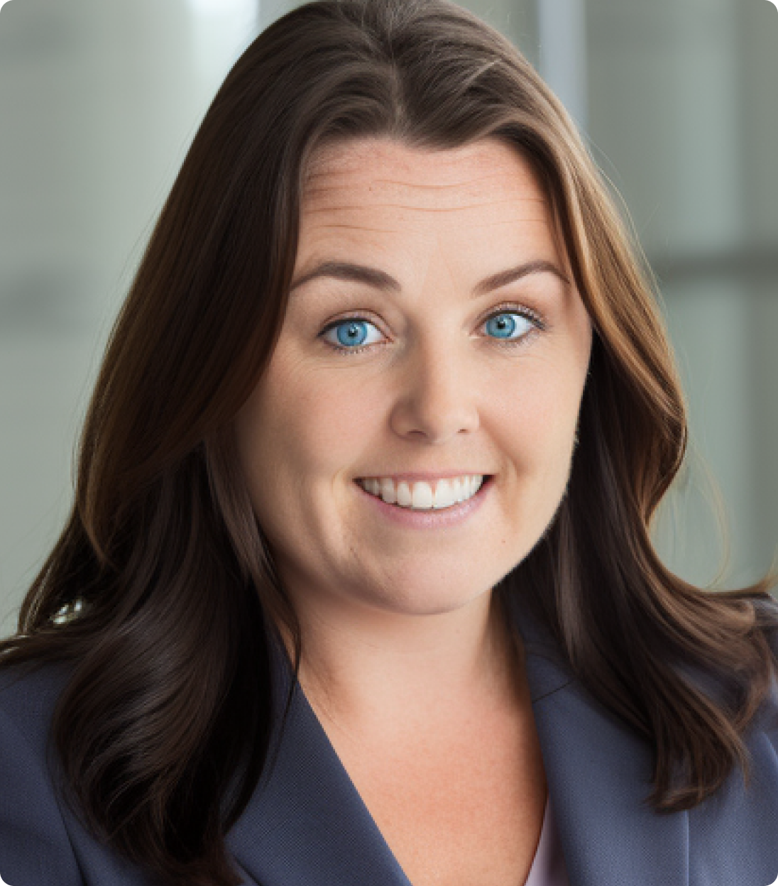 Smiling woman with long brown hair and blue eyes wearing a blue blazer.