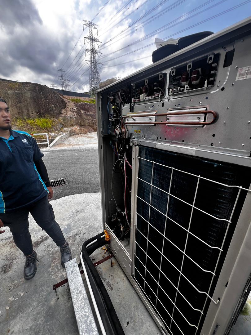 Technician inspecting aircond compressor unit