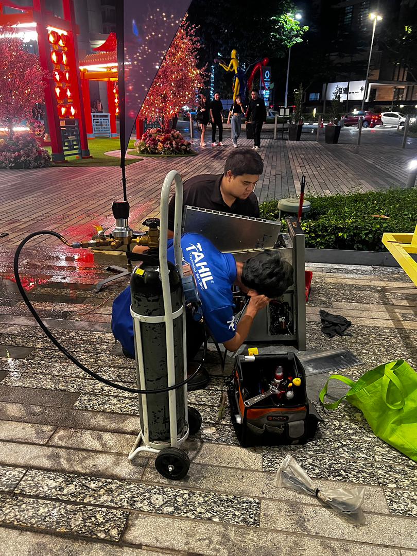 Technician inspecting aircond compressor unit