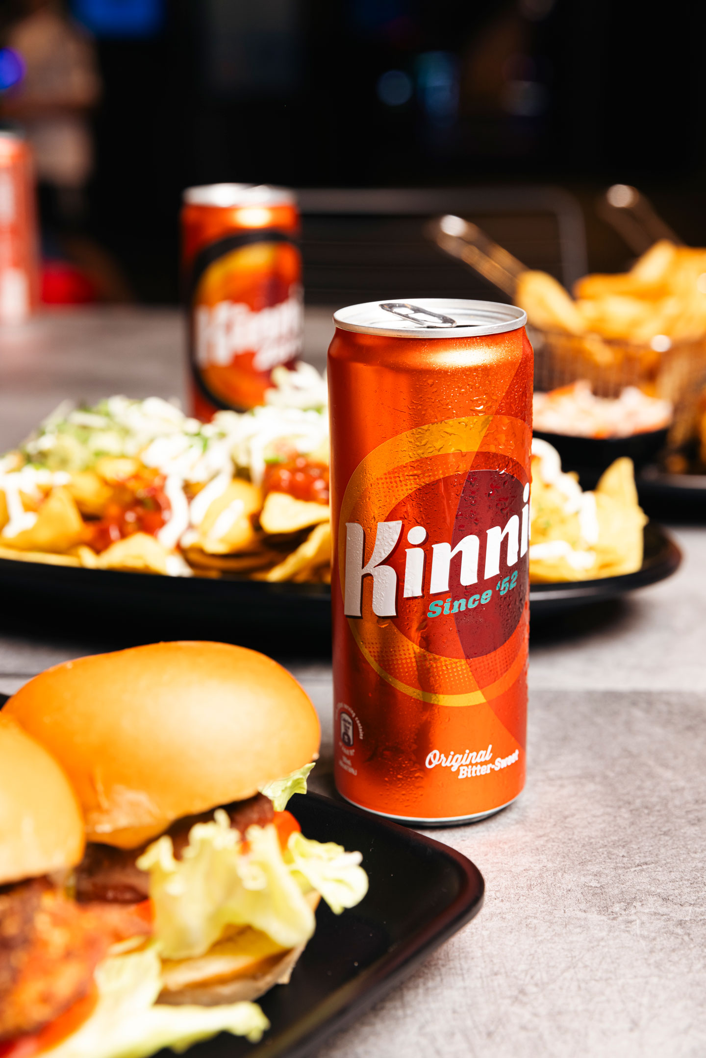 Can of Kinnie next to mini-burgers and nachos