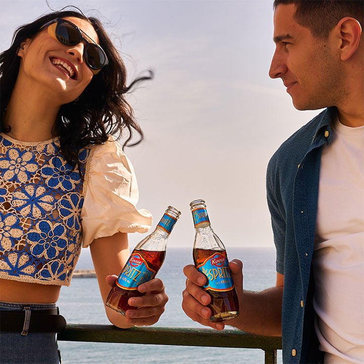 Couple enjoying Kinnie Spritz by the sea
