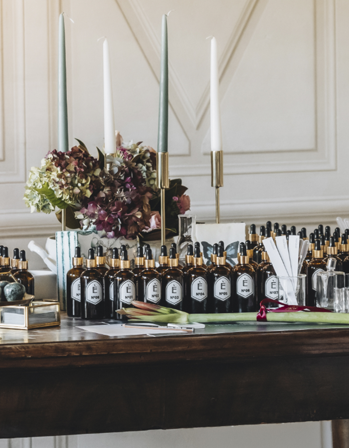 boccette di profumazioni Ephèmera disposte su tavolo con fiori e materiali naturali