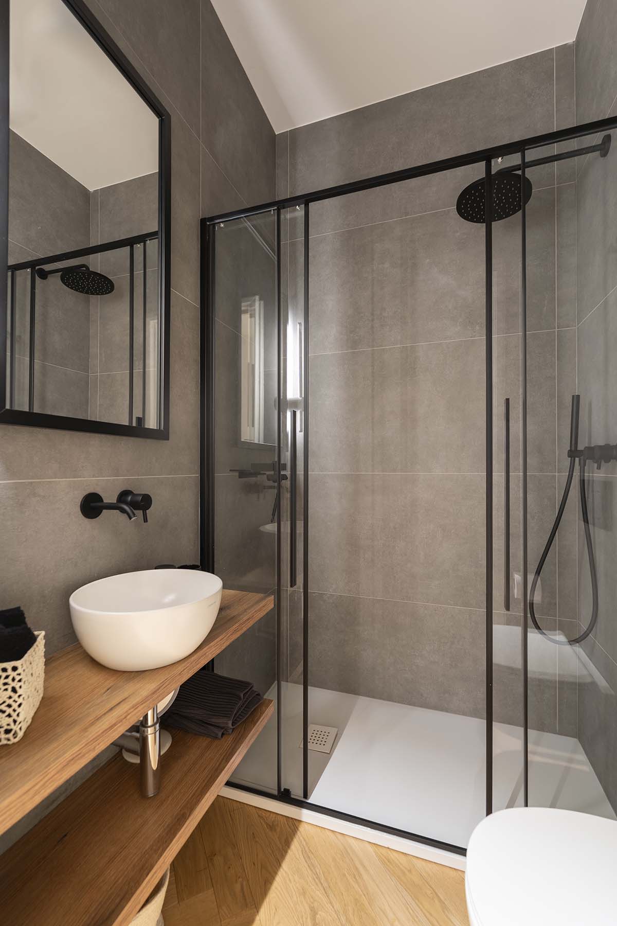 bagno con doccia e rivestimenti materici in appartamento a Milano in progetto di ristrutturazione completa