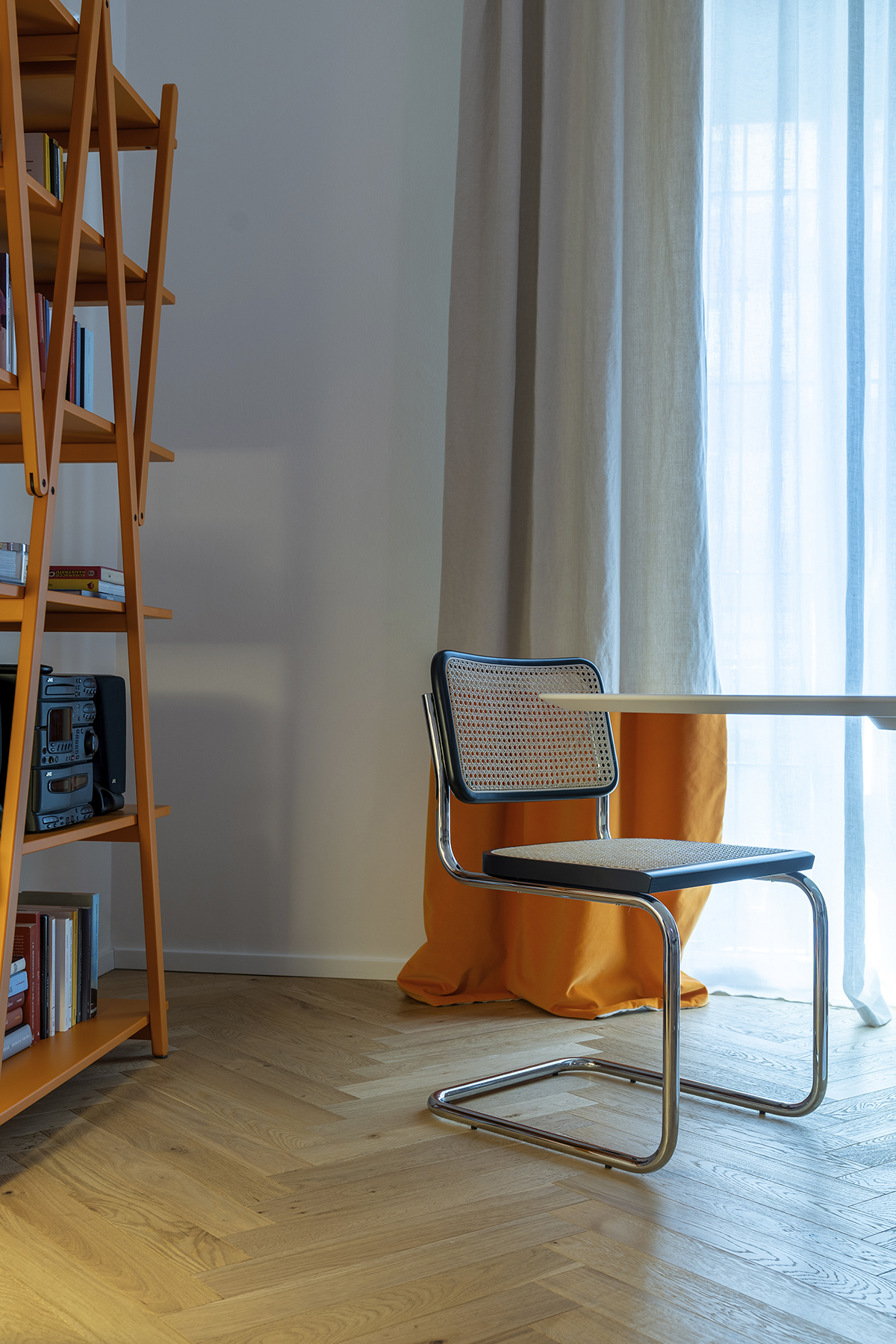 dettaglio sedia e libreria arancione in appartamento a Milano in ristrutturazione completa con design pop