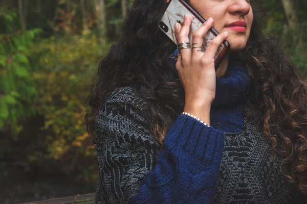woman in blue sweater holding smartphone