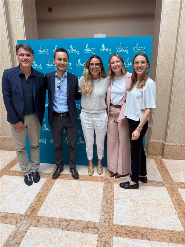 Uomo che presenta con microfono davanti a un pubblico seduto in una sala conferenze moderna con schermo digitale sullo sfondo.