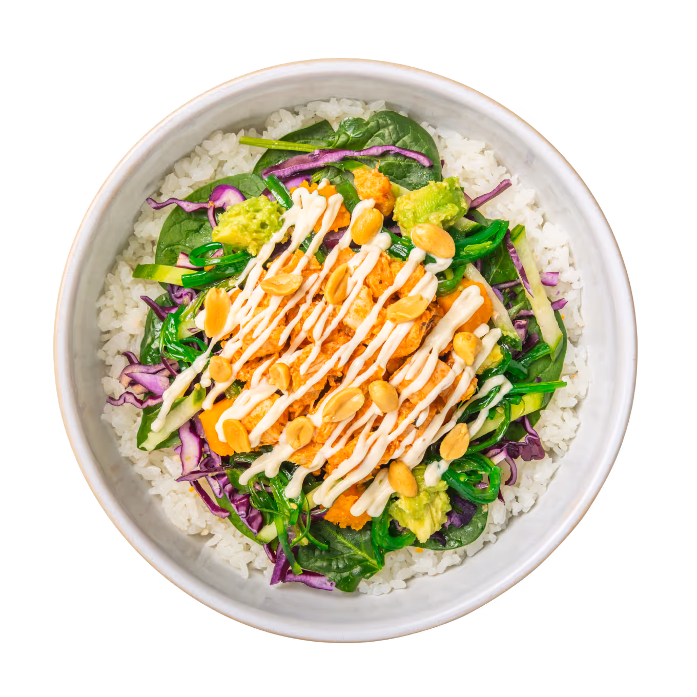 Eine farbenfrohe Schüssel Reis mit gemischtem Blattgemüse, gewürfelter Avocado, geraspelten Karotten, Rotkohl, beträufelt mit cremigem Dressing und bestreut mit Erdnüssen.