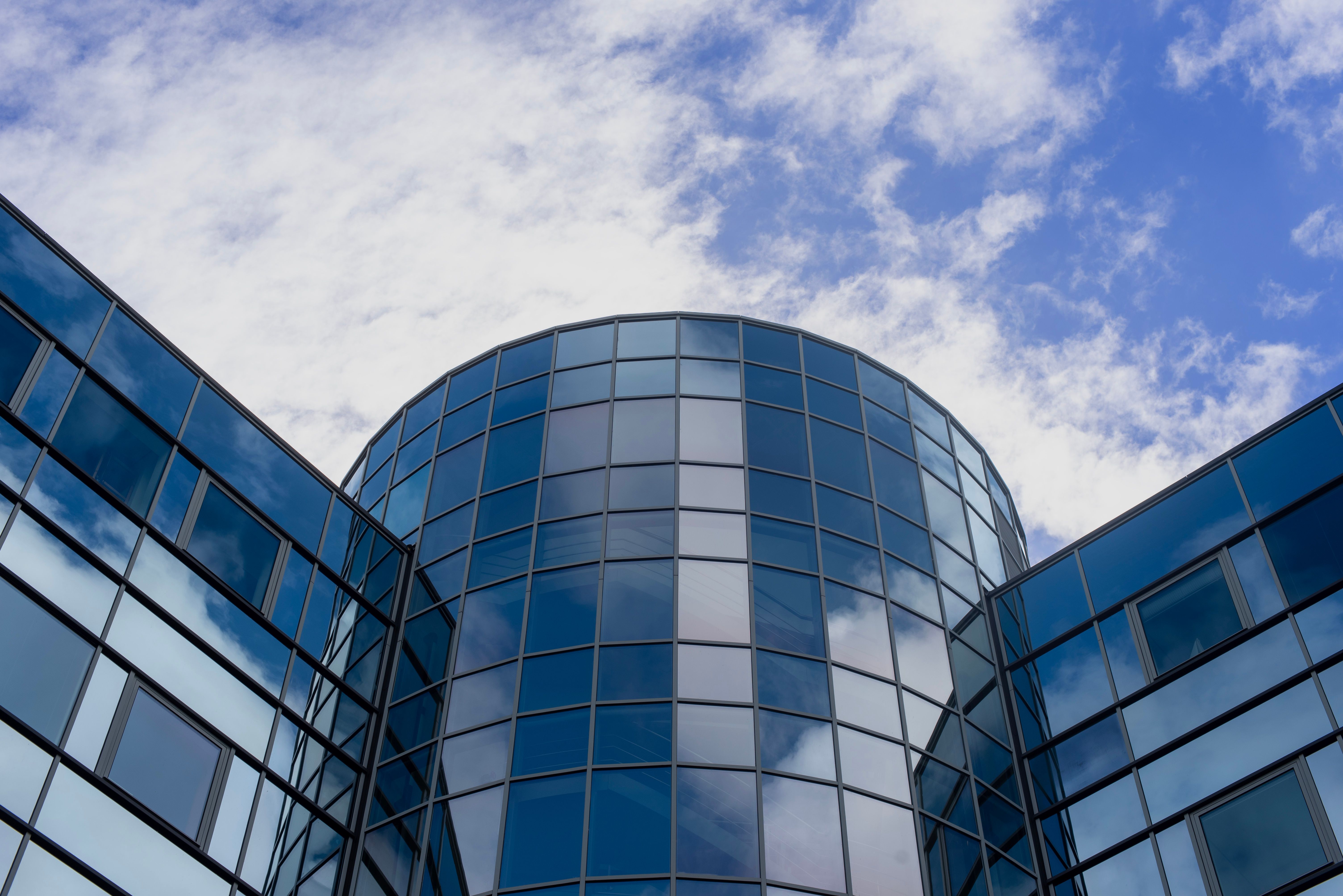 Looking up at a curved glass office building against the sky
