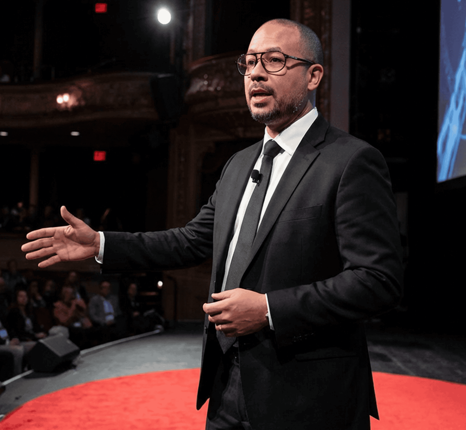 Grayscale photograph of a professional giving a presentation on a stage.