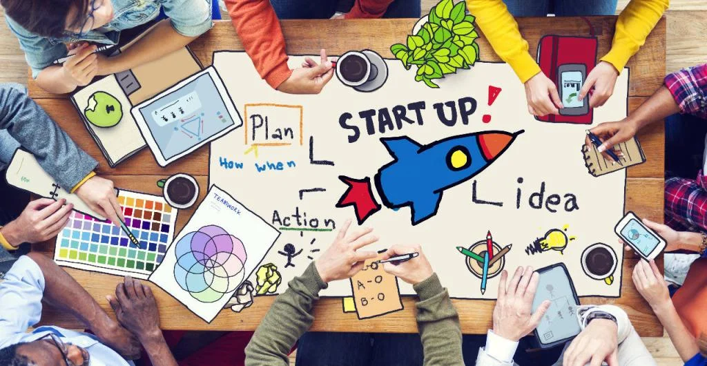 Un groupe de personnes travaille ensemble autour d'une table, sur laquelle est dessiné un plan pour une startup avec des idées et des actions, illustrant le processus et les perspectives de rendement d’un investissement en startup. 
