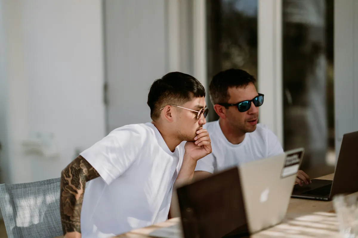 Deux hommes entrepreneurs proche mouvement FIRE en T-shirt blanc travaillant devant leurs ordinateurs
