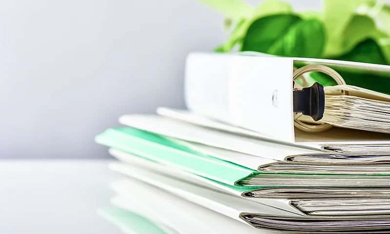 Des dossiers et classeurs empilés sur une table, symbolisant les inconvénients administratifs et la complexité de l'apport-cession.