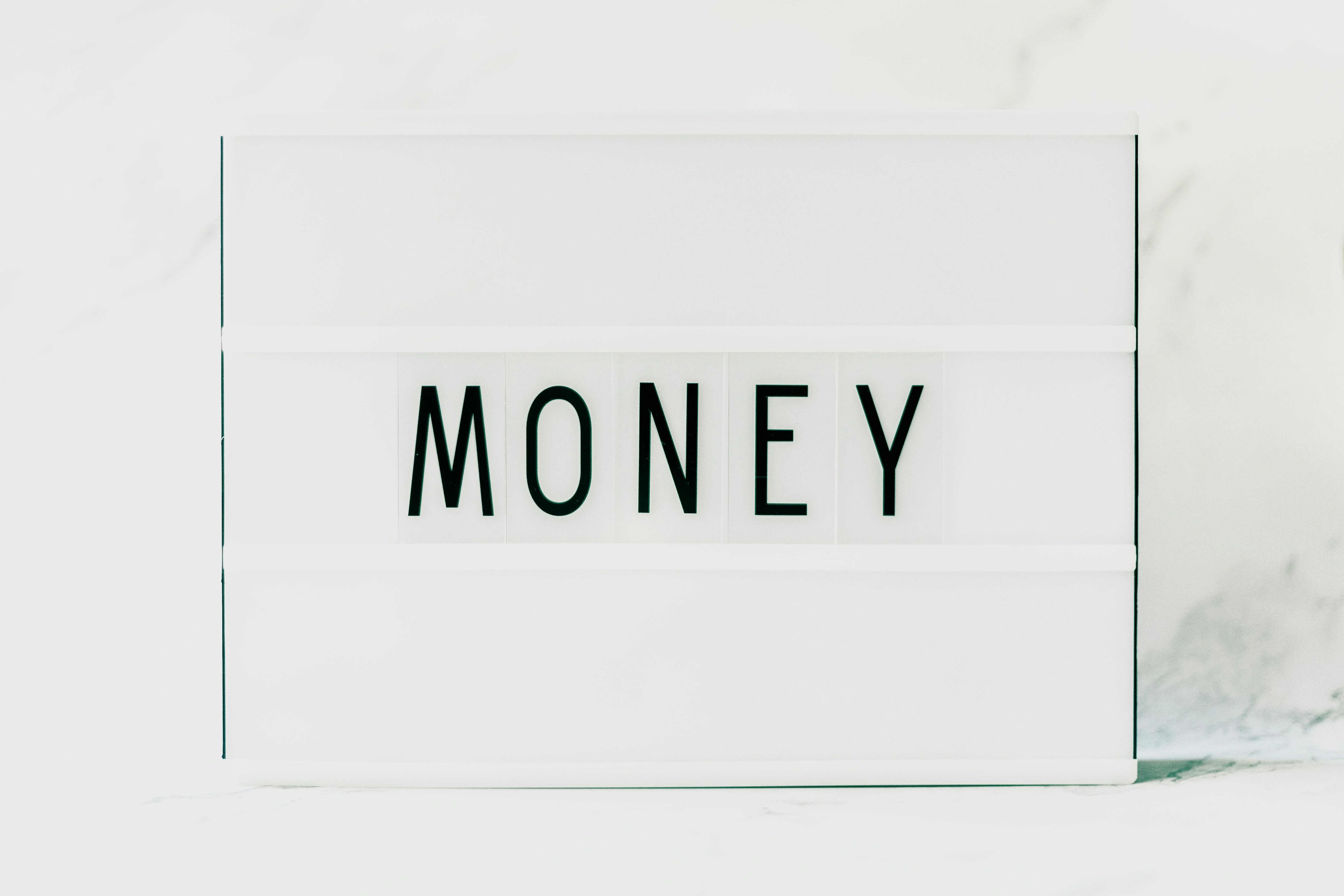 Panneau affichant "Money", symbolisant l'apport de titres à une holding pour optimiser la gestion financière.