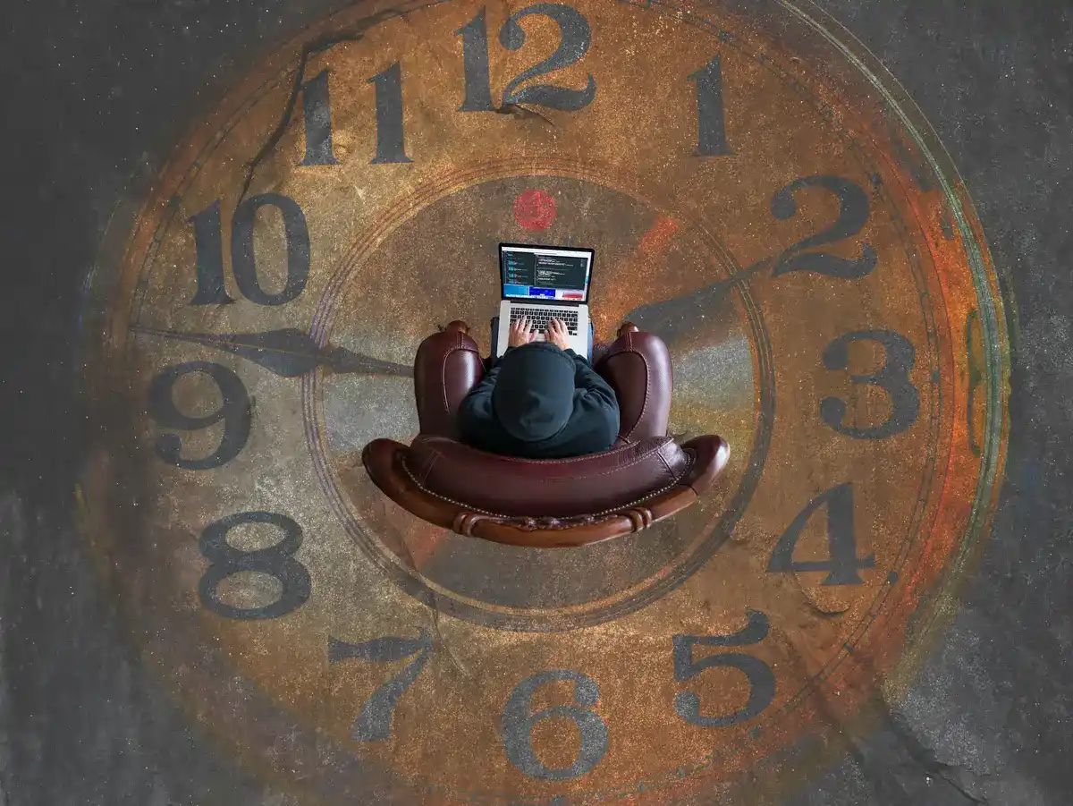 Individu sur un ordinateur vue d'en haut au milieu d'une grande horloge représentant le combat contre des forces plus grande comme la defiscalisation