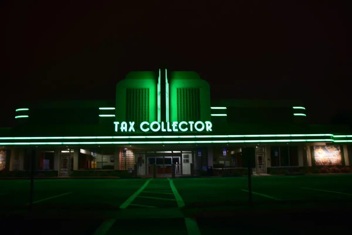 Batiment avec enseigne lumineuse verte "Tax collector"