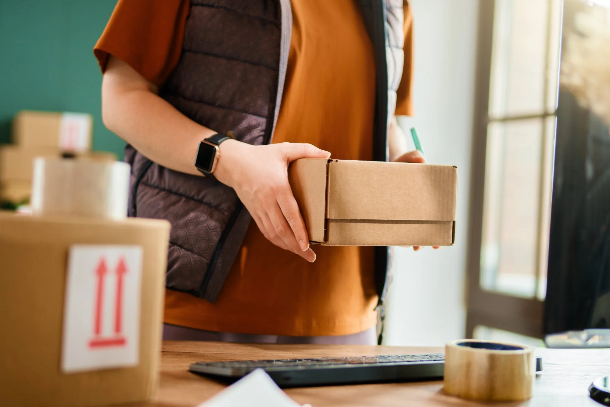 Person working in a warehouse packing cardboard boxes for online marketplace orders
