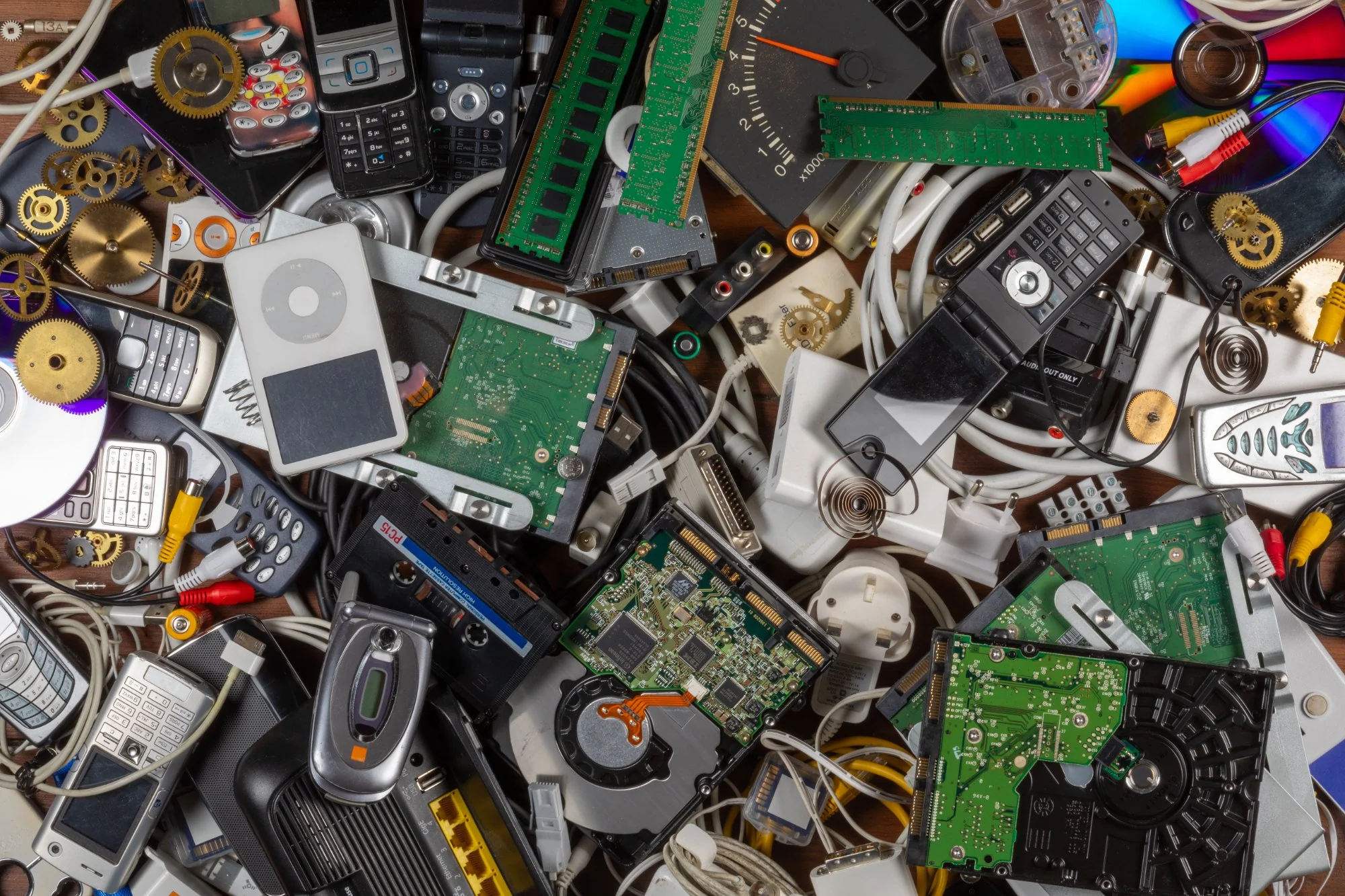 Pile of old electrical waste and end-of-life technology including mobile phones, circuit boards and cables ready for WEEE recycling