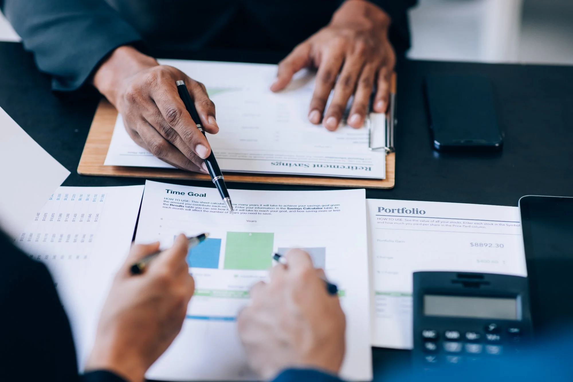 Close up of business people reviewing and discussing compliance documents and financial reports on a desk